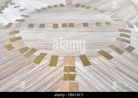 Impiallacciatura articolata con nastro per il piano del tavolo da pranzo con motivo geometrico sul banco di lavoro in primo piano in officina Foto Stock
