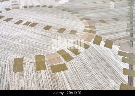 Impiallacciatura articolata con nastro per il piano del tavolo da pranzo con motivo geometrico sul banco di lavoro in primo piano in officina Foto Stock