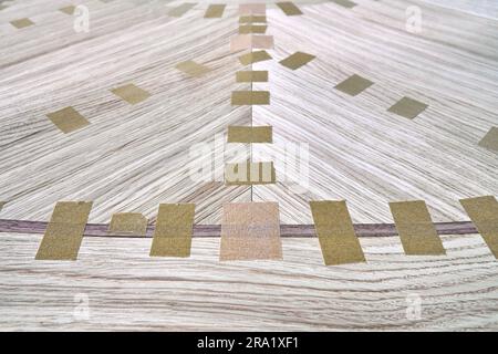 Impiallacciatura articolata con nastro per il piano del tavolo da pranzo con motivo geometrico sul banco di lavoro in primo piano in officina Foto Stock