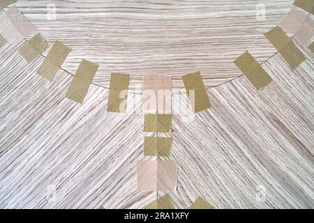 Impiallacciatura articolata con nastro in tela per il piano del tavolo da pranzo con motivo geometrico sul banco di lavoro nella vista ravvicinata superiore dell'officina Foto Stock