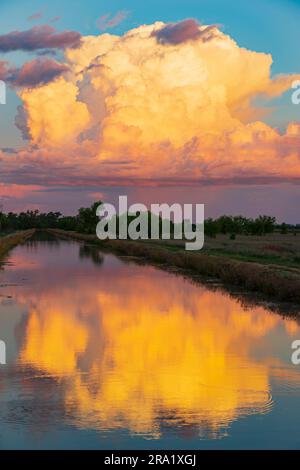 Vista aerea delle nuvole di temporali colorate riflesse nelle calme acque di un canale agricolo, a St George nel Queensland, Australia Foto Stock
