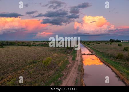Vista aerea delle nuvole di temporali colorate riflesse nelle calme acque di un canale agricolo, a St George nel Queensland, Australia Foto Stock