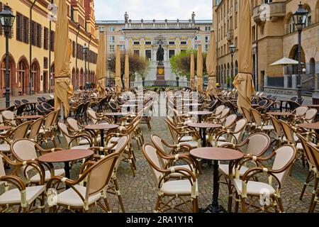 Sedie e tavoli vuoti sul Naschmarkt la mattina presto, il monumento di Goethe e alte Boerse sullo sfondo, Germania, Sassonia, Lipsia Foto Stock