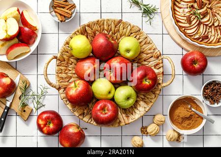 Apple. Mele fresche crude rosse e verdi in un cestino su un tavolo da cucina con ingredienti per cucinare torta di mele autunnale del Ringraziamento, vista dall'alto Foto Stock