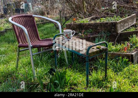 Una sedia in un'area pronta per il giardiniere a sedersi, riposarsi e prendere una tazza di tè. Il tavolo è improvvisato da un inginocchiato. Foto Stock