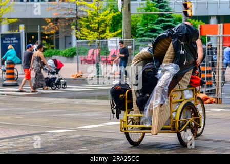 Una persona sposta oggetti personali su un triciclo nel quartiere del centro. Foto Stock