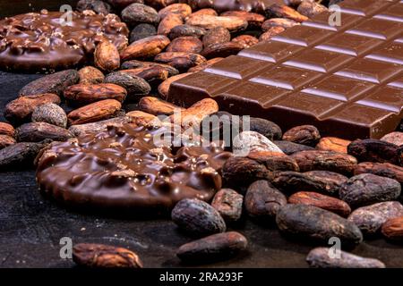 Tavoletta di cioccolato al latte accompagnata da biscotti immersi nel cioccolato e da diversi ingredienti. Foto Stock