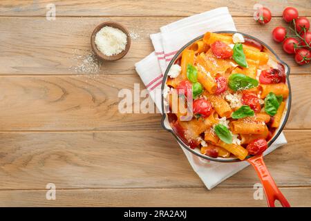 Tortiglioni di pasta con salsa di pomodoro, pomodori ciliegini al forno, mozzarella e parmigiano, basilico su fondo rustico antico. Italiano tradizionale Foto Stock