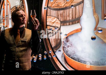 Scotch Whisky Experience, Royal Mile, Edimburgo, Scozia, Regno Unito, 30 giugno 2023. Apertura di una nuova esperienza immersiva: Tre sale con proiezioni multimediali conducono i visitatori attraverso la birreria di whisky scozzese, che si aggiunge all'attrazione turistica a 5 stelle. Nella foto: La guida Corin Rhys Jones tiene un bicchierino di whisky. Crediti: Sally Anderson/Alamy Live News. Foto Stock