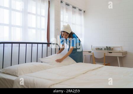 Donna asiatica cameriera che organizza un cuscino sul materasso in camera da letto a casa. Foto Stock