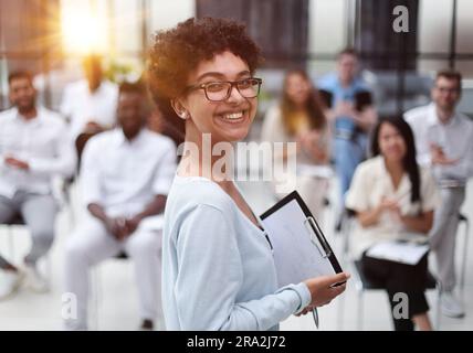 Focalizzazione selettiva della giovane donna d'affari insieme ai colleghi interrazziali durante il seminario Foto Stock