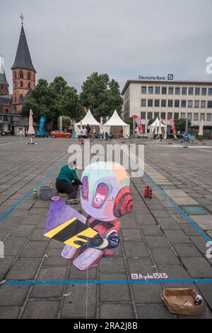 Kaiserslautern, Germania. 30 giugno 2023. L'artista messicana Ayde Juarez (Ayde1313) finirà il suo dipinto 3D. Undici artisti internazionali provenienti da 6 paesi hanno trasformato la pavimentazione Stiftsplatz (piazza) in arte tridimensionale, con "digitalizzazione e Smart City" come argomento di quest'anno. La Street art 3D utilizza la prospettiva per creare illusioni ottiche dello spazio. I visitatori erano invitati a guardare tutti gli artisti al lavoro per tre giorni. Questo è il terzo e ultimo giorno dell'evento. Credito: Gustav Zygmund/Alamy News Foto Stock