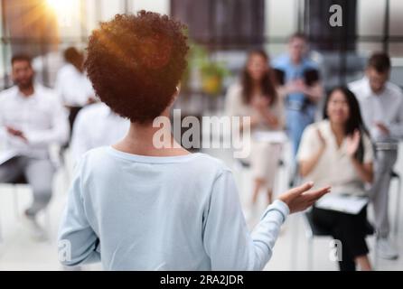 Focalizzazione selettiva della giovane donna d'affari insieme ai colleghi interrazziali durante il seminario Foto Stock