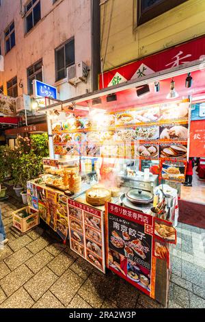 Bancarelle di cibo da asporto cinese di notte a Nankinmachi, Chinatown, Kobe. Il banco vende panini cotti al vapore e gyoza, i panini cotti in contenitori di bambù. Foto Stock