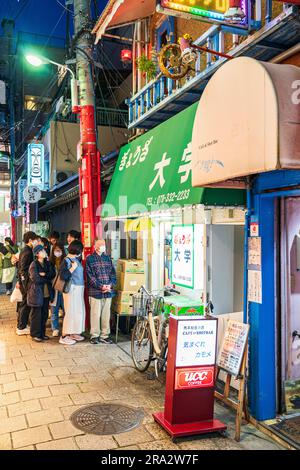 I giapponesi fanno la fila in serata fuori dall'entrata del famoso negozio Gyoza Daigaku nella Chinatown di Kobe, Nankinmachi. Foto Stock