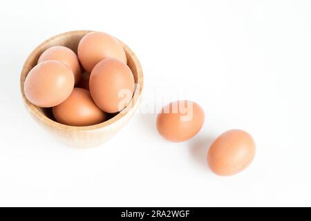 Diverse uova di gallina fresche poste dentro e fuori un contenitore di bambù su sfondo bianco. Vista dall'alto e spazio di copia. Foto Stock