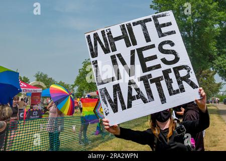 HUDSON, WISCONSIN, Stati Uniti d'America - 17 GIUGNO 2023: Individuo mascherato non identificato che tiene il banner White Lives Matter alla celebrazione dell'Hudson Pride. Foto Stock