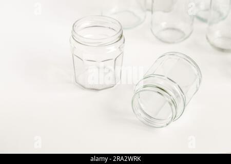 Set assortito di contenitori in vetro senza coperchi su sfondo bianco, riciclaggio. Concetto di seconda vita rispetto ai materiali, vari usi per fiale in vetro. Foto Stock