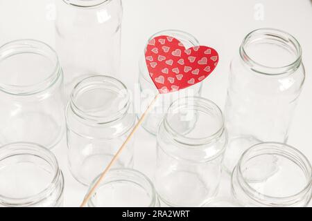 Set assortito di contenitori in vetro senza coperchi su sfondo bianco, riciclaggio. Concetto di seconda vita rispetto ai materiali, vari usi per fiale in vetro. Foto Stock