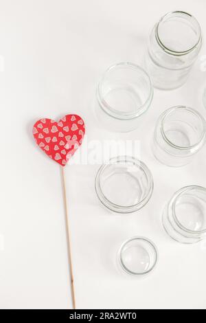 Set assortito di contenitori in vetro senza coperchi su sfondo bianco, riciclaggio. Concetto di seconda vita rispetto ai materiali, vari usi per fiale in vetro. Foto Stock