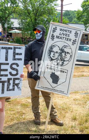 HUDSON, WISCONSIN, Stati Uniti d'America - 17 GIUGNO 2023: Individuo mascherato non identificato che tiene il banner White Lives Matter alla celebrazione dell'Hudson Pride. Foto Stock