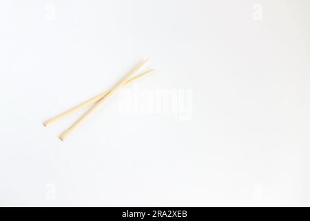 Coppia di bacchette di bambù per una persona isolata su sfondo bianco. Ampiamente usato nella cultura orientale e asiatica. Foto Stock