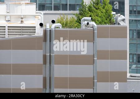 Tubi di ventilazione che salgono fino al tetto sulla parete esterna di un edificio alto Foto Stock