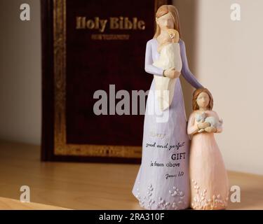 Ornamento in ceramica a tema cristiano di una madre con la figlia e il bambino, con "ogni regalo buono e perfetto è dall'alto Giacomo 1:17". Foto Stock