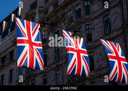 Bandiere Union Jack che volano, si bunting, in una trafficata strada di Londra. Le bandiere rosse, bianche e blu del Regno Unito sono un simbolo di libertà e orgoglio per la gente. Foto Stock