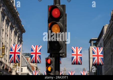 Semaforo giallo e rosso su una strada cittadina di Londra con bandiere inglesi. Segnali contrastanti e confusi, metafora concettuale per scelte di vita. Foto Stock