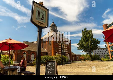 Woolwich London, Dial Arch Pub con un cartello Quiz Night sulla lavagna in Dial Arch Square con la Royal Brass Foundry in Royal Arsenal sullo sfondo. Foto Stock
