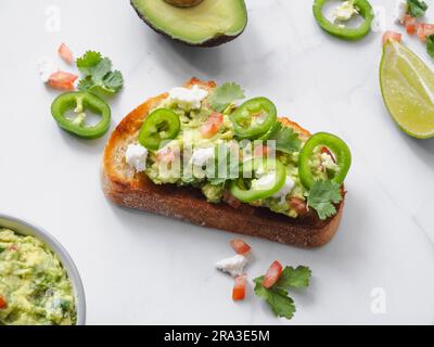 guacamole di avocado schiacciato su pane tostato con coriandolo, pomodoro, queso fresco e jalapeno. Cucina messicana tradizionale e autentica Foto Stock