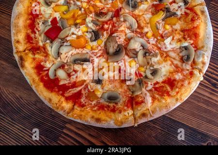 Funghi pizza: Una pizza appetitosa condita con salsa di pomodoro, formaggio fuso, funghi saporiti, peperoni vivaci e mais dolce, tutti serviti su una rus' Foto Stock