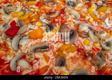 Funghi pizza: Una pizza appetitosa condita con salsa di pomodoro, formaggio fuso, funghi saporiti, peperoni vivaci e mais dolce, tutti serviti su una rus' Foto Stock