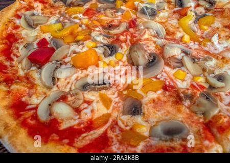 Funghi pizza: Una pizza appetitosa condita con salsa di pomodoro, formaggio fuso, funghi saporiti, peperoni vivaci e mais dolce, tutti serviti su una rus' Foto Stock