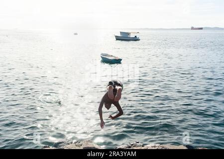 Salvador, Bahia, Brasile - 14 gennaio 2022: Un giovane è visto saltare dal molo di Praia do Mam nella comunità Gamboa a Salvador, Bahia. Foto Stock