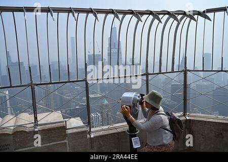 Le persone visitano la piattaforma di osservazione dell'Empire State Building mentre il fumo degli incendi canadesi ricopre lo skyline di Manhattan il 30 giugno 2023 a New Yo Foto Stock