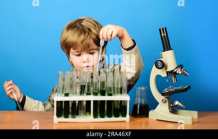 Ragazzo intelligente che lavora con provette per test e microscopio in classe scolastica. Studio di biologia e chimica dei bambini. Esperimento educativo. Materia scolastica. Ragazzino Foto Stock