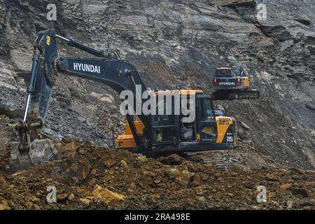 Gli escavatori Hyundai rompono le rocce e rimuovono i detriti dopo una frana lungo la National Highway 150 dopo una forte pioggia monsonica alla periferia di Churachandpur, Manipur Churachandpur si trova in una regione collinare ed è soggetta a frane, soprattutto durante la stagione dei monsoni. Le forti piogge e i ripidi pendii in questa zona aumentano il rischio di frane. Fattori quali l’erosione del suolo, la deforestazione, l’uso improprio del suolo e le attività di costruzione possono anche contribuire al verificarsi di frane. Foto Stock