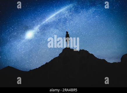 Silhouette di donna in montagna sotto il cielo stellato di notte Foto Stock