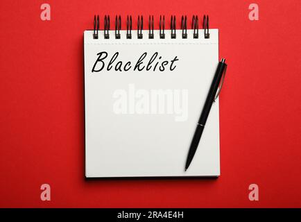 Lista nera di Word scritta in blocco note su sfondo rosso, vista dall'alto Foto Stock