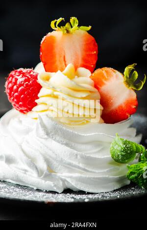 Meringa italiana croccante al forno con centro di marshmallow, ripiena di crema Chantilly, condita con fragole fresche e lamponi. Foto Stock