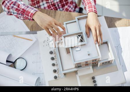 Architetto maschio che tiene e lavora sul modello di vista dall'alto della casa architettonica Foto Stock