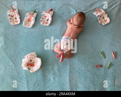 Foto del neonato sdraiato su una coperta e circondato da pannolini Foto Stock