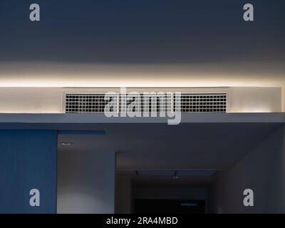 Aria condizionata, sistema di ventilazione a parete sul soffitto nella camera bianca dell'hotel, vista frontale. Griglia di ventilazione della camera d'albergo sulla parete. Foto Stock