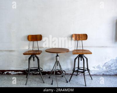 Sedie vuote vintage filanti schienale, sedile e tavolino rotondo decorati su vecchie pareti bianche, interni di un edificio in stile loft. Swive Foto Stock