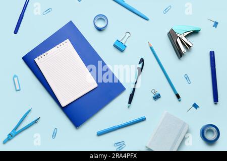 Composizione con notebook vuoto e materiali di consumo per cancelleria su sfondo blu Foto Stock