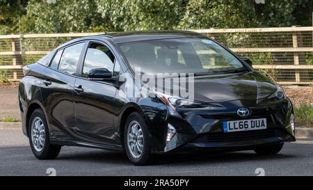 Milton Keynes, Regno Unito - 24 giugno 2023. 2016 auto elettrica ibrida TOYOTA PRIUS nera che viaggia su una strada di campagna inglese Foto Stock