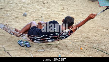 Un uomo riposa su un'amaca sulla spiaggia di Jomtien, Pattaya, Thailandia, Foto Stock