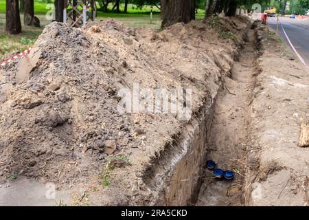 Lavori in terra, scavo di trincee. Viene scavata una lunga trincea per la posa di tubi. Riparare in città. Foto Stock